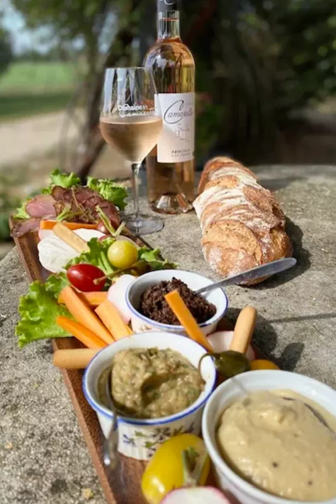 Plateau apéritif avec légumes, tapenade, et pain, accompagné d'une bouteille et d'un verre de vin rosé