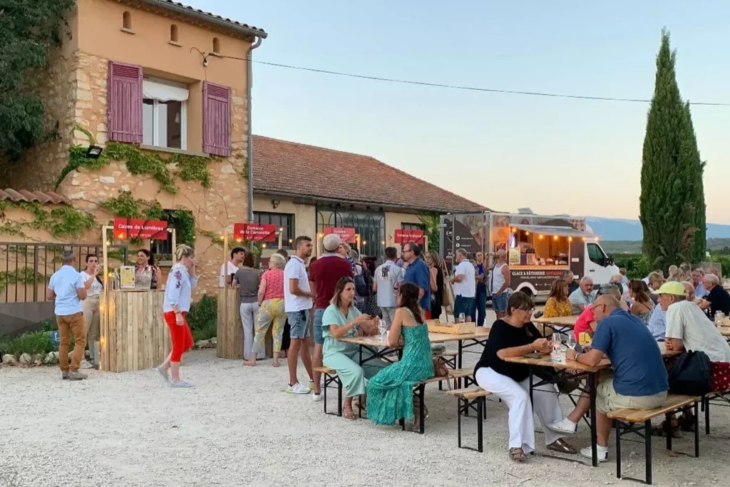 Groupes de personnes participant à une activité d'oenotourisme au Domaine La Camarette, dégustant et socialisant autour de tables en plein air