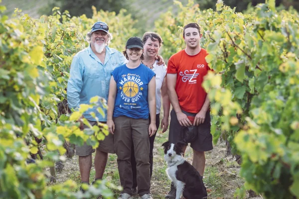 Quatre membres de la famille posent dans les vignes, avec un chien assis au premier plan