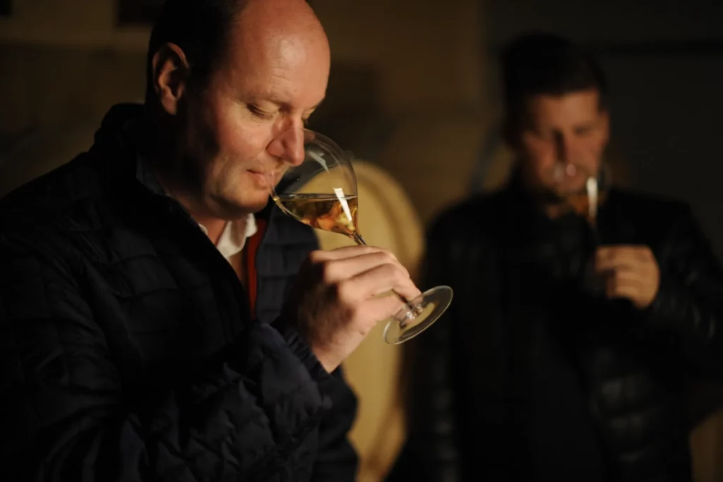 Champagne Régis Poissinet - Régis Poissinet goûte un vin au verre dans le chai