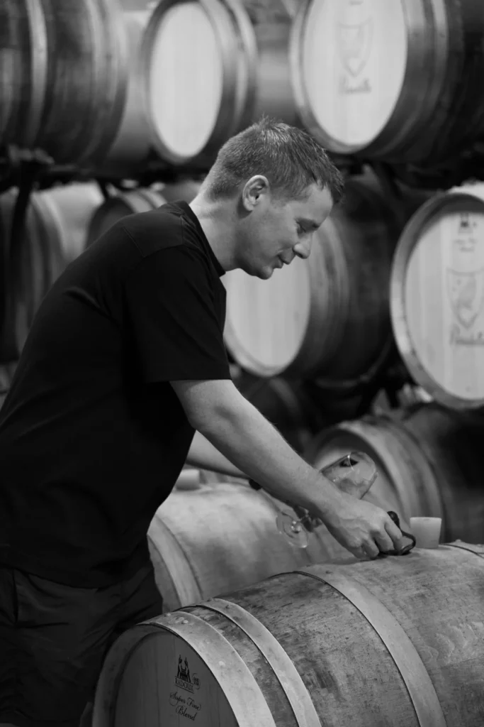 Domaine Paradella - Lionel Wojcik penché sur une barrique marquée au blason du domaine