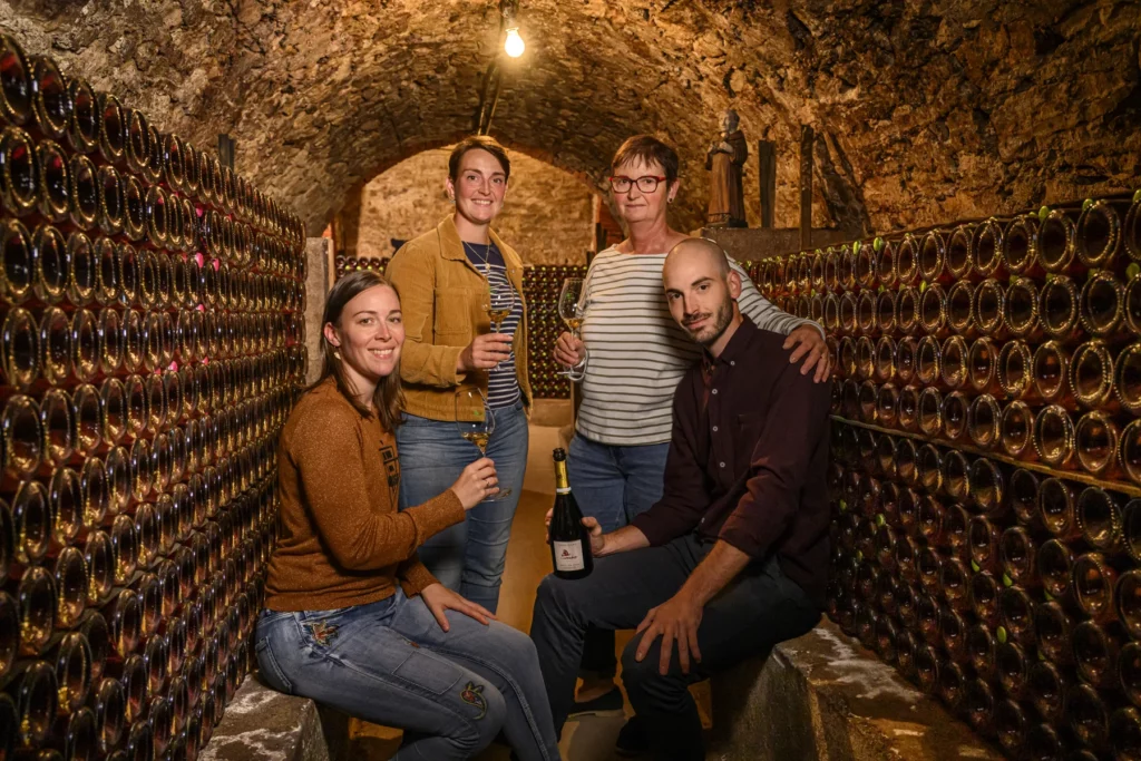 Champagne De Sousa - La famille réunie dans une galerie de la cave, entre les bouteilles en tas