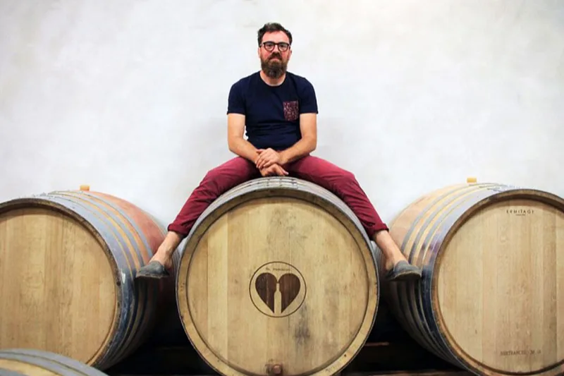 Château Barouillet - Vincent Alexis assis sur des fûts dans le chai