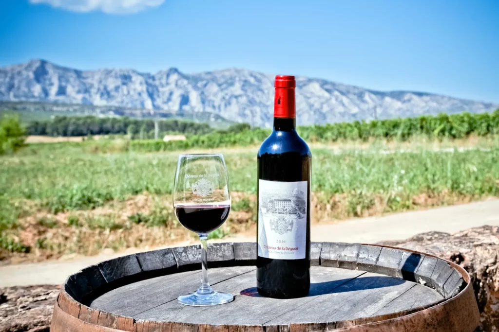 Château de la Bégude - Une bouteille de rouge et un verre posés sur un fût, la Sainte-Victoire au fond