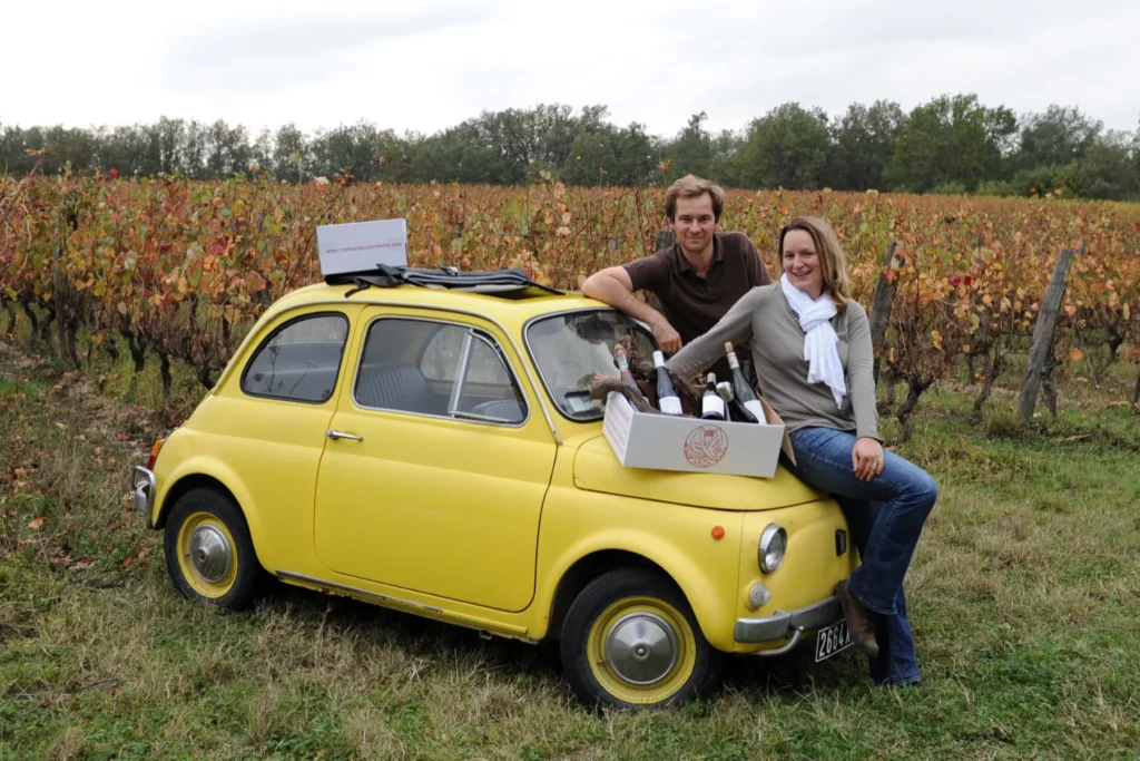 Domaine La Colombière - Philippe et Diane Cauvin assis sur une voiture jaune au milieu des vignes d’automne
