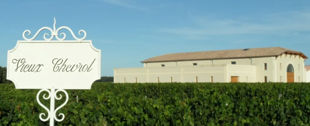 Château Vieux Chevrol - Le panneau du domaine devant le chai et les vignes à Néac