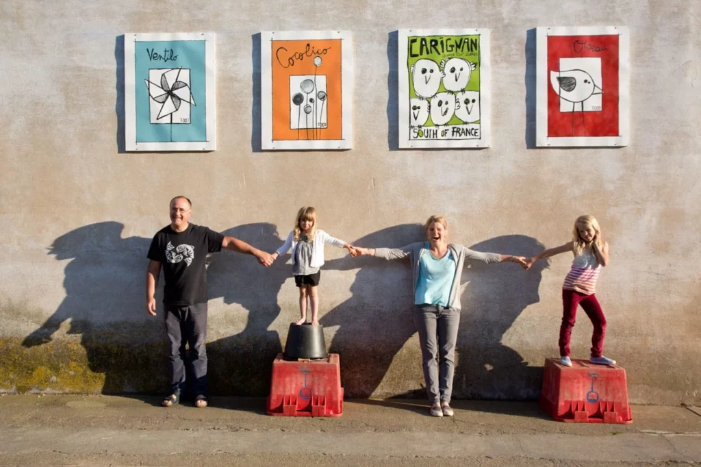 Colline de l’Hirondelle - La famille main dans la main sous les étiquettes peintes en grand sur un mur