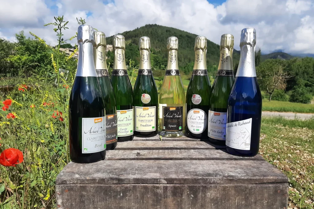 Domaine Achard-Vincent - Les effervescents du domaine alignés sur une caisse en bois, dans un pré fleuri