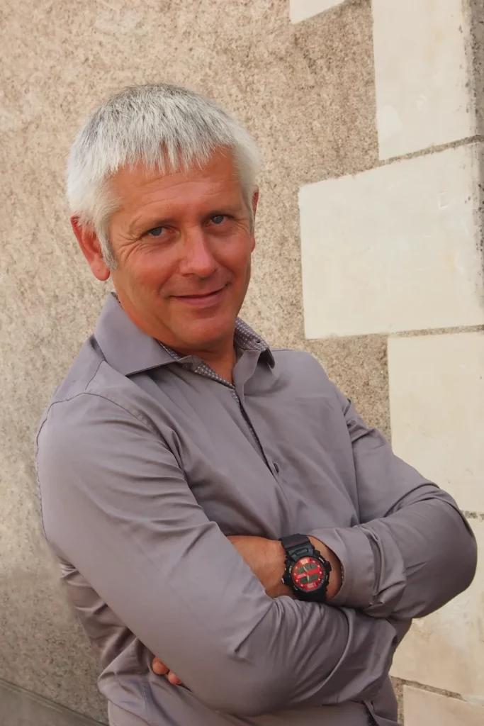 Domaine Allias - Dominique Allias, vigneron, bras croisés contre un mur de tuffeau