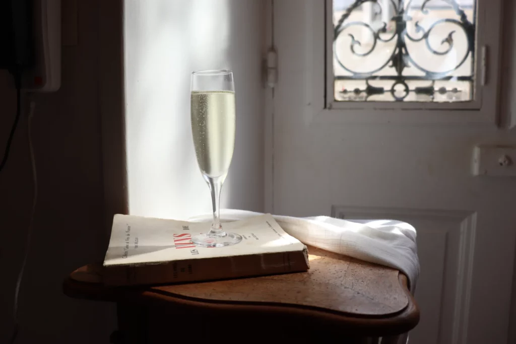 Domaine Allias - Flûte de fines bulles posée sur un vieux livre de vins, près d’une fenêtre