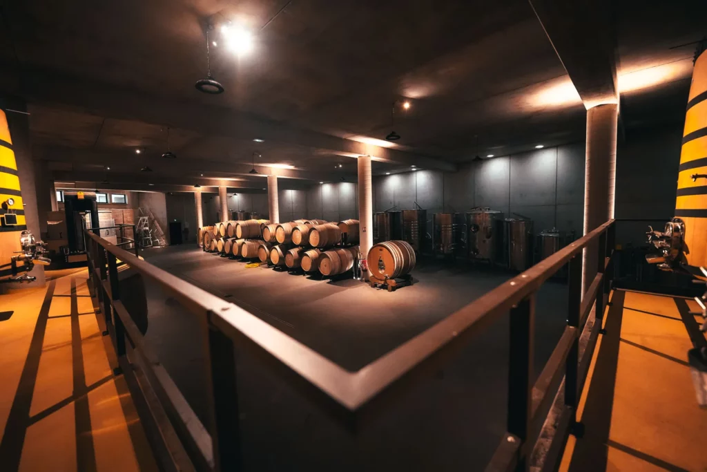 Domaine Comte Abbatucci - Les fûts du chai vus depuis la galerie, sous un éclairage tamisé