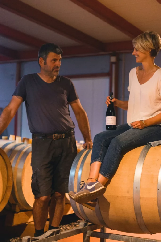 Domaine de la Ville Rouge - Audrey Girard assise sur une barrique, Sébastien Girard debout à côté, dans le chai