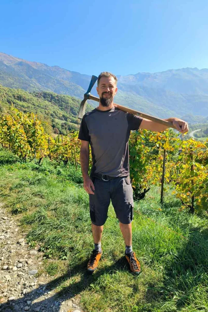Domaine de l’Aitonnement - Maxime Dancoine, une pioche sur l’épaule, sur un chemin des vignes