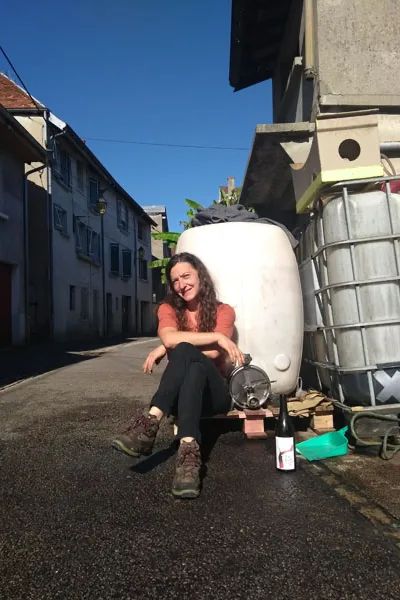 Domaine de l'Octavin - Alice Bouvot assise près d'une cuve, une bouteille à ses pieds