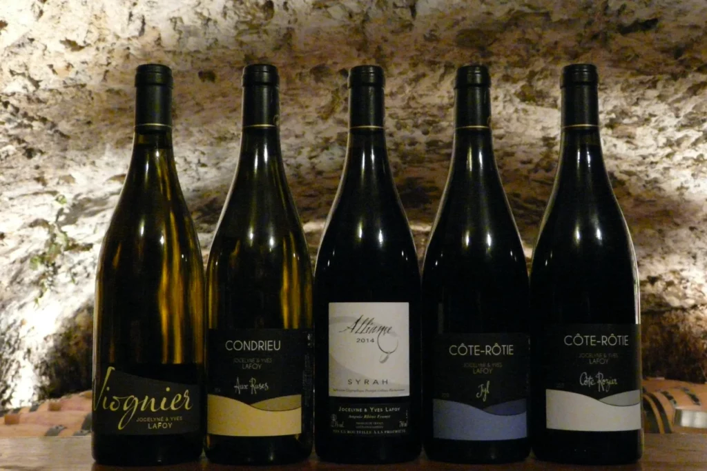 Domaine Lafoy - Les cinq vins du domaine alignés devant le mur de pierre de la cave