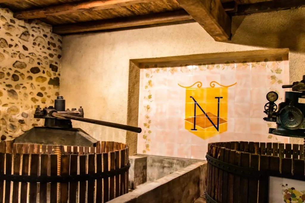 Domaine Nigri - Deux pressoirs anciens devant l’écusson N peint au mur du chai