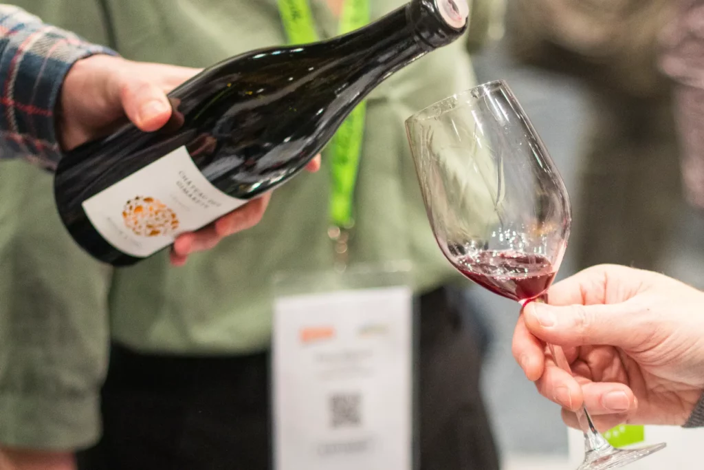 Salon des vins Demeter & La Levée de la Loire à Paris - Un vigneron verse du vin rouge dans le verre d’un visiteur