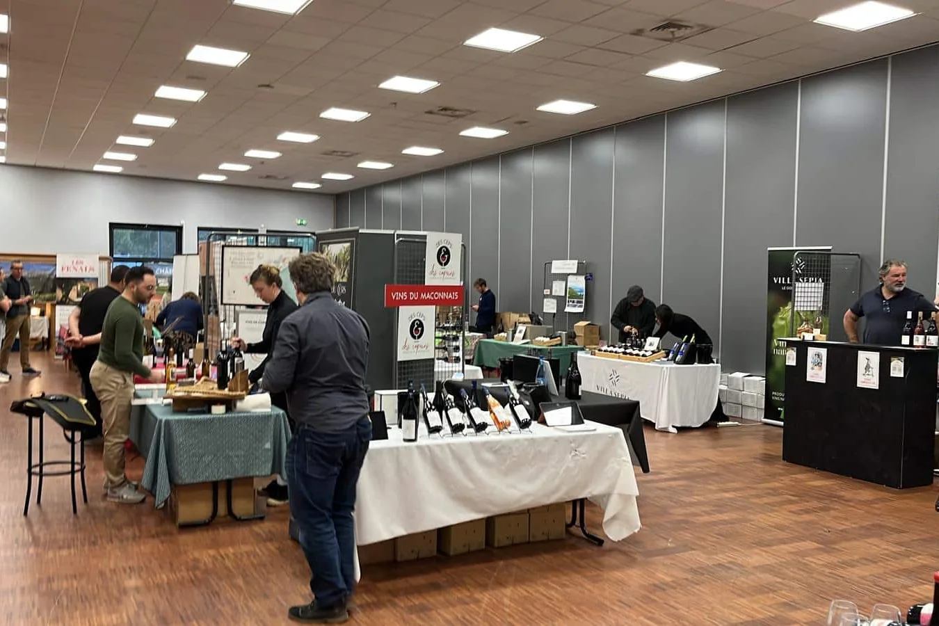 Salon du Vin Bio d’Annecy - Stands de vignerons nappés de blanc dans la salle Cap Périaz, visiteurs en dégustation