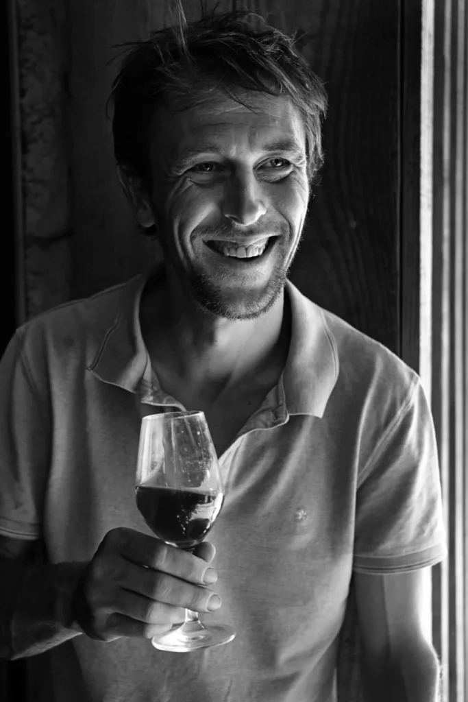 Vignerons Curtet - Florian Curtet, un verre de vin rouge à la main